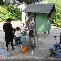 Eltern pflegen Kita-Außengelände und Kinder bepflanzen